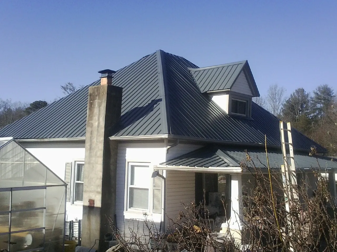 Dark blue standing seam metal roof on a white farmhouse with dormer — Slate & Tile Roof Repair by Roofing Brothers in Cornersville