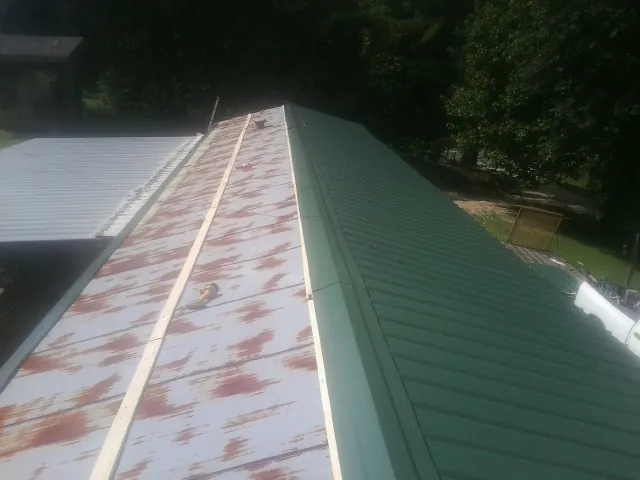 Old rusted panels beside newly installed green metal roofing — Wind Damage Roof Repair by Roofing Brothers in Cornersville