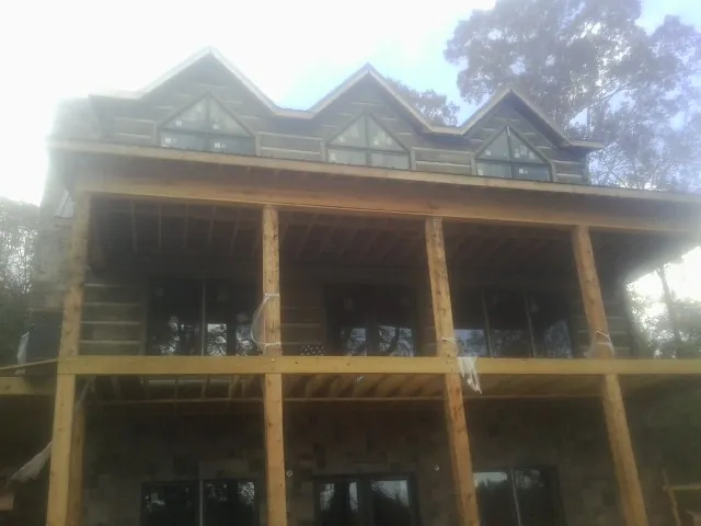 Dormers and porch framing on a large log home under construction — Roof Coating work by our crew in Cornersville