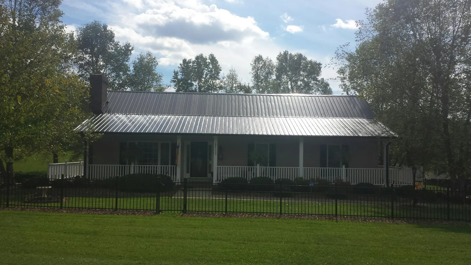 Gray metal roof on a brick ranch with a full width front porch — Gutter Guard Installation work by our crew in Cornersville