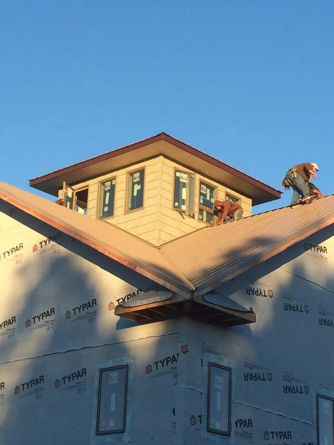 Roofers working around a rooftop cupola on a new metal roof at sunset — Roof Waterproofing in Cornersville by Roofing Brothers